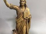 statue en bronze représentant une femme tenant un livre et pointant le ciel du doigt