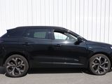 Le SUV noir est garé devant un immeuble blanc.