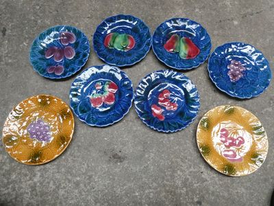 six assiettes ornées de motifs différents, posées par terre