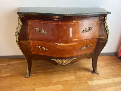 a wooden chest of drawers with a marble top on a hard wood floor