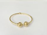 a close up of a gold bracelet with two balls on it