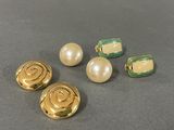 three pairs of gold and pearl buttons on a gray surface