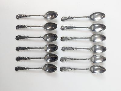 six cuillères en argent sont alignées sur une surface blanche