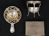 Deux objets en argent sont posés sur une surface noire, à côté d'un miroir.