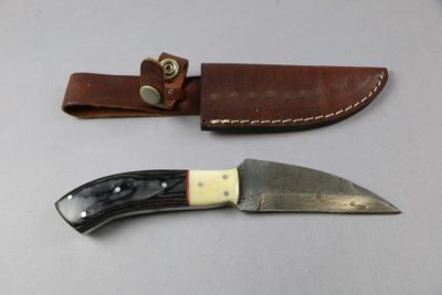 a knife that is sitting next to a leather sheath