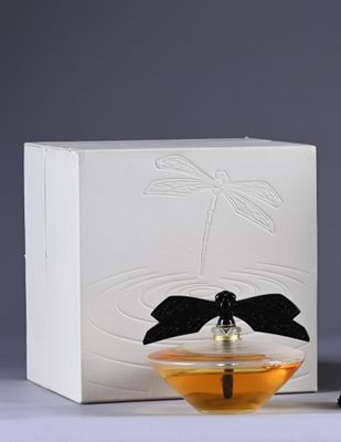 a bottle of perfume next to a box with a dragonfly on it