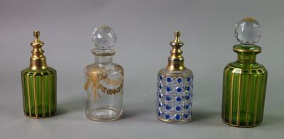 four different colored glass bottles are lined up on a white surface