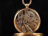 a close up of a gold pocket watch on a black surface