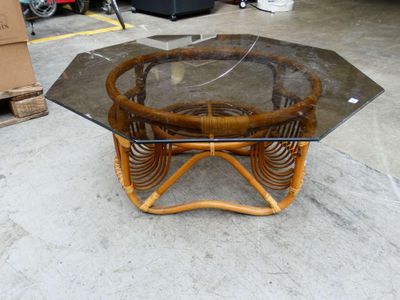 une table avec un plateau en verre et un piètement en osier