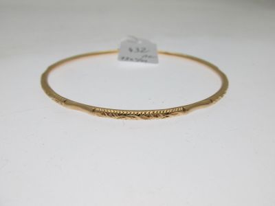 gros plan d'un bracelet en or sur une surface blanche