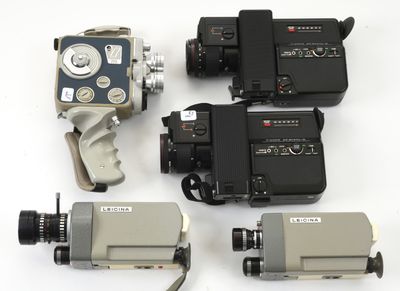 trois vieilles caméras de cinéma posées les unes à côté des autres sur une surface blanche