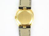 a gold watch on a black strap on a white surface