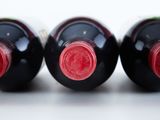 three bottles of red wine are lined up on a white surface