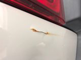 a close up of a rusted tail light on a white car