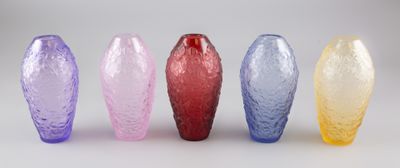 quatre vases de couleurs différentes posés côte à côte sur une surface blanche