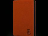 un gros plan sur un carnet en cuir orange sur fond noir