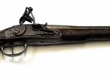 un vieux pistolet surmonté d'un homme, posé sur une surface blanche