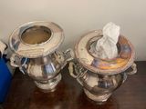 two silver teapots sitting on a table next to each other