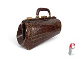 une image représentant un sac à main en peau de crocodile marron sur fond blanc