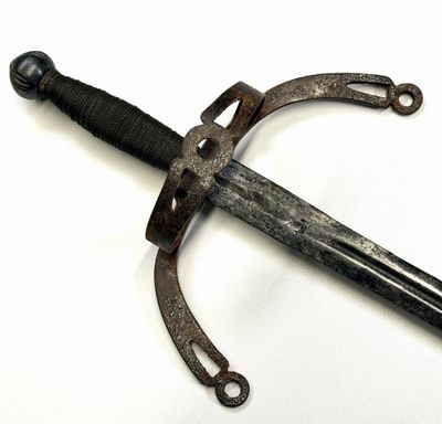 une épée d'aspect très ancien posée sur une surface blanche