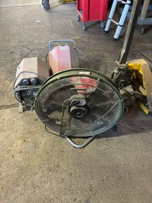 a fan that is sitting on the ground next to a cart