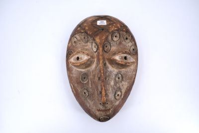 un masque en bois accroché à un mur, sur fond blanc