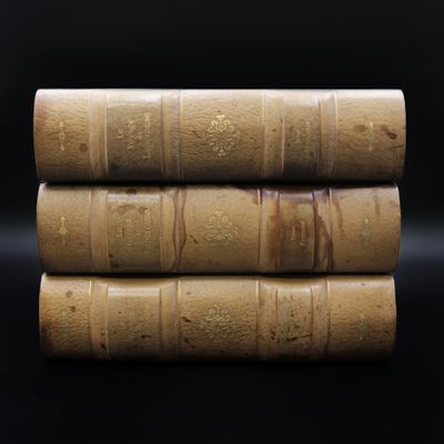 trois vieux livres empilés les uns sur les autres sur une surface noire