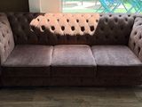 a brown couch sitting in a living room next to a window