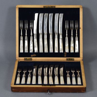 un service d'argenterie dans un coffret en bois posé sur une table