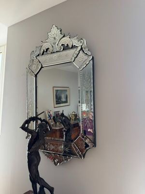 a mirror hanging on the wall above a statue of a man