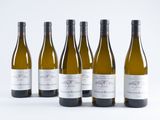 six bottles of wine are lined up in a row on a white surface
