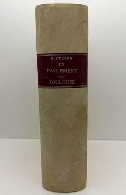 un vieux livre posé sur une table à côté d'un mur blanc