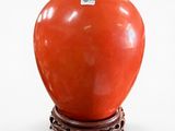 a red vase with a black lid sitting on a stand