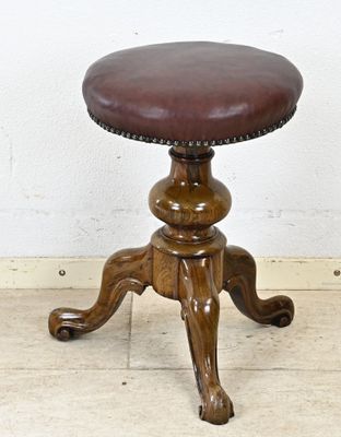 un tabouret marron avec une assise en cuir posé sur un sol en bois