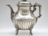 an antique silver tea pot with a handle on a white surface