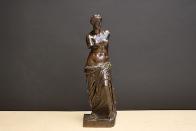 bronze statue of a woman holding a vase on a table