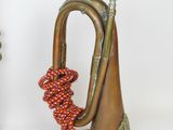 two brass trumpets with red and orange beads on them