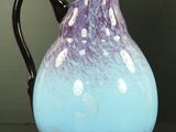 un pichet en verre violet et bleu posé sur une table