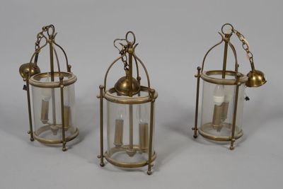 three brass and glass lanterns on a white background