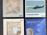 quatre livres dans leur boîte posés sur une table, avec un avion en arrière-plan