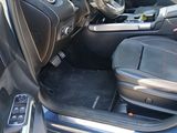 the interior of a car with the door open and the driver ' s seat down