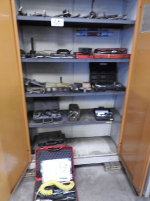 une petite armoire ouverte sur laquelle sont posés des outils, dans une pièce