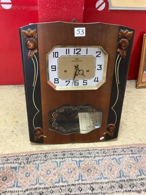 une horloge posée par terre devant un tableau