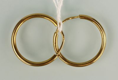 paire de boucles d'oreilles créoles en or avec un fil blanc sur fond blanc