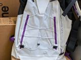 purple and white backpack sitting on top of a box next to a carton of luggage