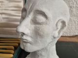 a white sculpture of a man ' s head on a table