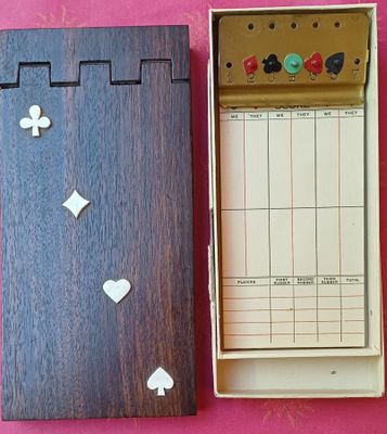 une boîte en bois contenant un jeu de cartes, posée sur une surface rose