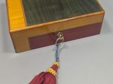 a small wooden box with a tassel hanging from it