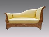 une chaise longue ancienne en bois, avec une assise rembourrée jaune