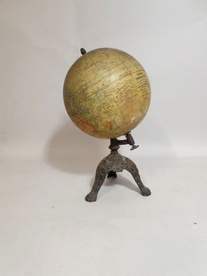 un globe en laiton ancien posé sur un trépied, avec un fond blanc
